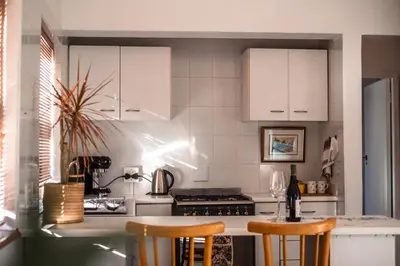 a kitchen with white cabinets and a table with chairs at Luxury suite near Church Street in Stellenbosch