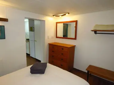 a bedroom with a bed and a dresser and a mirror at De Kelder in Cape Town
